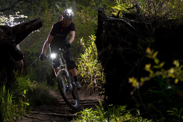 Mountain biker using lights mounted to both the handlebars and their helmet