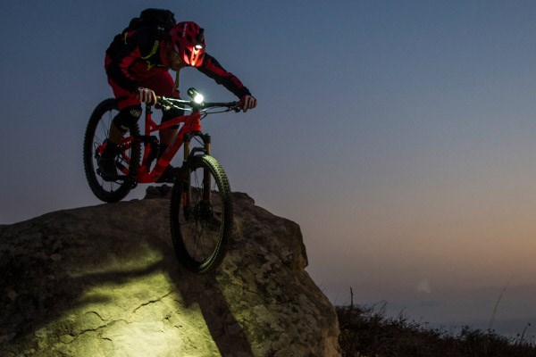 Mountain biker using advanced Exposure lights on both helmets and handle bars