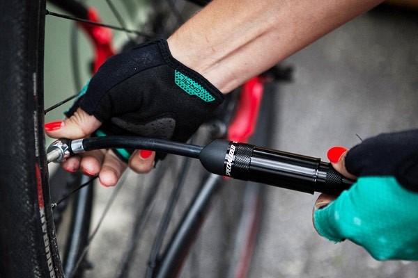 A mini hand pump inflating a bike tyre