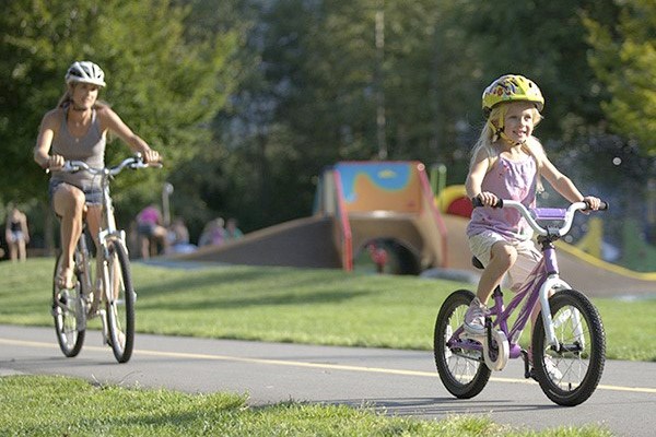 A mother and daughter cycling through a park together