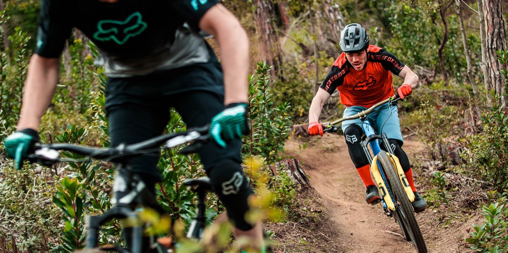 A downhill mountain biker wearing Fox Clothing and Protective Equipment