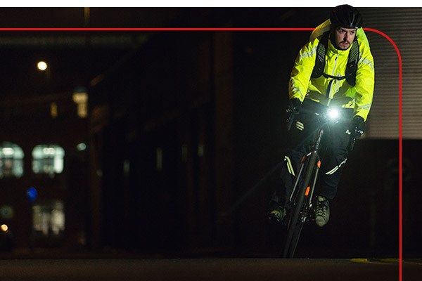 A cycle commuter riding in the city, with a light at night