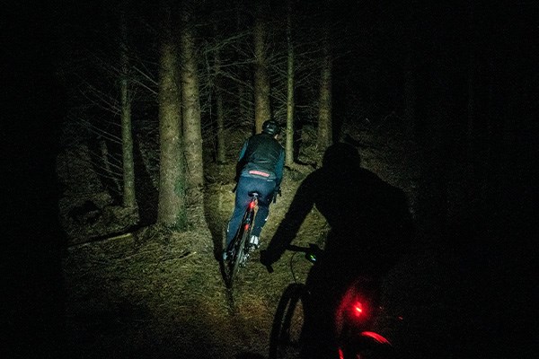 Gravel bike riders at night with lights in the woods