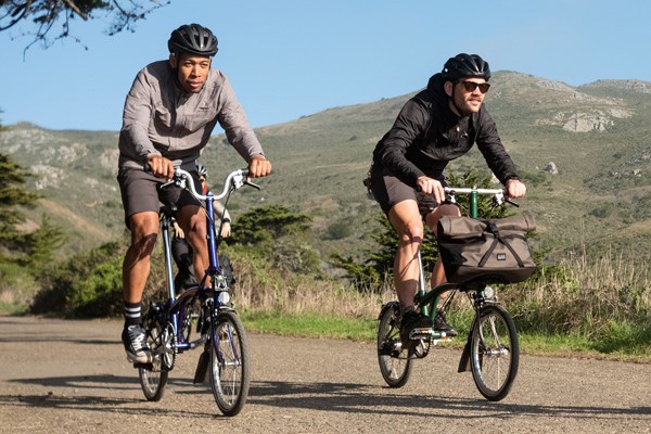 Two riders on Bromptons cycling country lanes