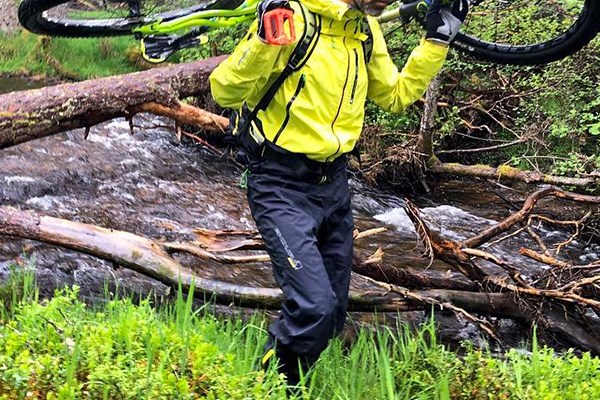 rider in waterproof trousers carrying the bike