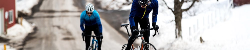 Two road cyclists riding through a snowy town