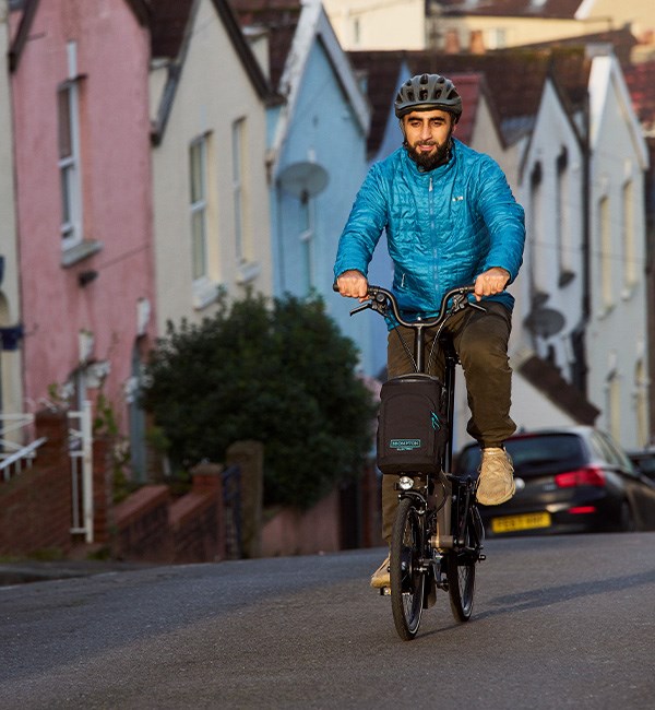 man riding a Brompton Electric folding bike up hill