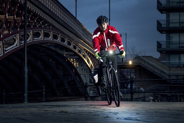 A road cyclist uses a lower-powered light to aid visibility in a busy urban environment
