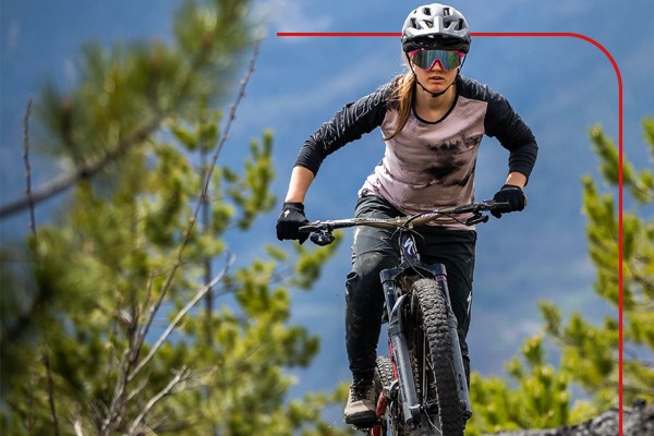 A mountain biker riding a Merida electric hardtail mountain bike through an overgrown trail