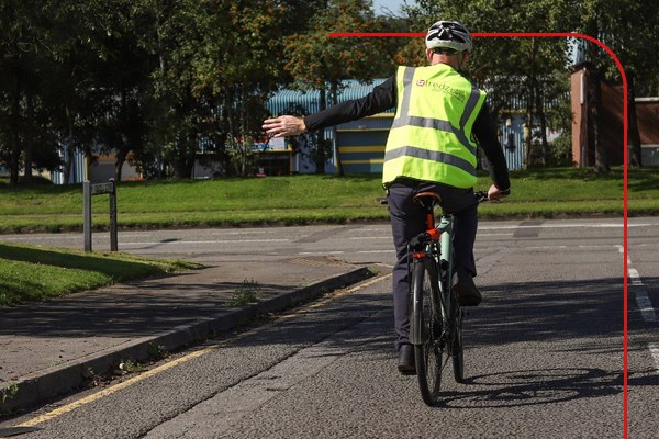 A cyclist turning left onto a main road