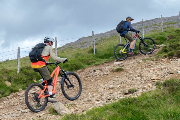 two MTBers riding e-bikes up a steep incline in the Welsh mountains