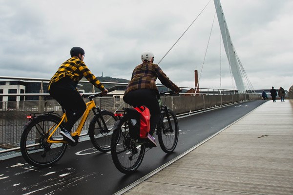 Two cyclists ride across a bridge on Ebikes