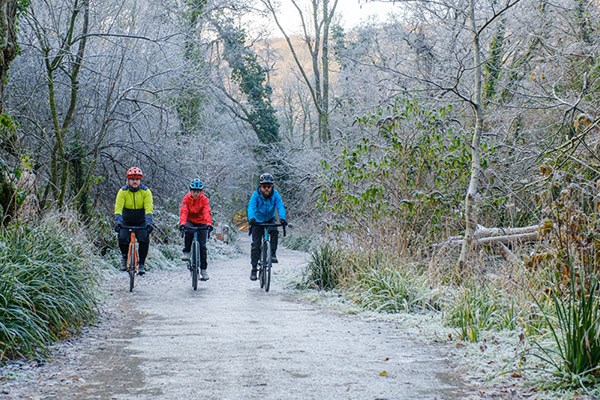 Cyclists riding along a gravel path in winter