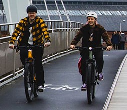couple riding electric bikes accross a bridge in the city